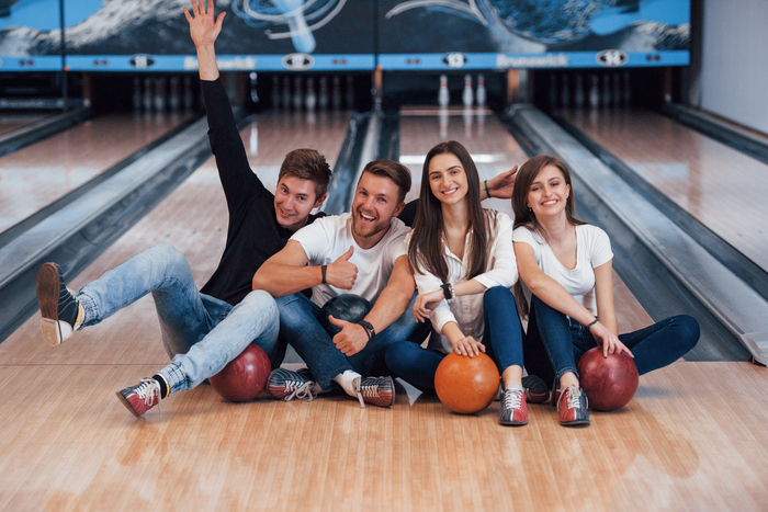 Guy have fun with arms raised up. Young cheerful friends have fun in bowling club at their weekends.